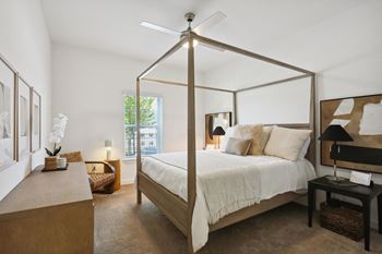 A bedroom with a four poster bed and a table with a lamp on it at Arcadia Cartersville Apartments, Cartersville, GA